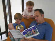 Wes Brown, right, reads to children Shawn Larimer-Brown, 7, left, and Charlie Larimer-Brown, 5, center, at their home Aug. 18 in Winter Park, Fla.