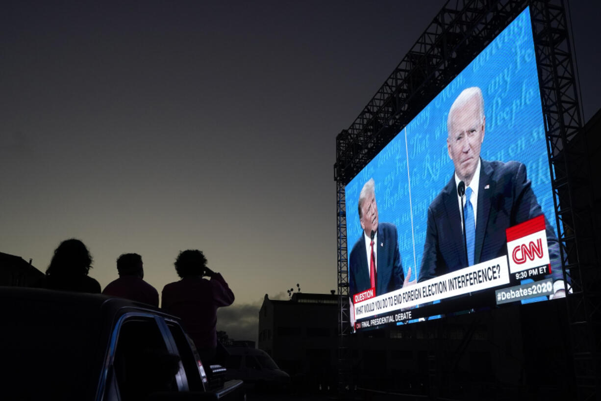 FILE - People watch from their vehicle as President Donald Trump, on left of video screen, and Democratic presidential candidate former Vice President Joe Biden speak during a Presidential Debate Watch Party at Fort Mason Center in San Francisco, Thursday, Oct. 22, 2020. Unflattering portraits of both Biden and Trump emerge clearly in a new poll by The Associated Press-NORC Center for Public Affairs Research, which asked an open-ended question about what comes to mind when people think of them.