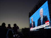 FILE - People watch from their vehicle as President Donald Trump, on left of video screen, and Democratic presidential candidate former Vice President Joe Biden speak during a Presidential Debate Watch Party at Fort Mason Center in San Francisco, Thursday, Oct. 22, 2020. Unflattering portraits of both Biden and Trump emerge clearly in a new poll by The Associated Press-NORC Center for Public Affairs Research, which asked an open-ended question about what comes to mind when people think of them.