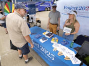 Kristen Eichamer, right, and Spencer Chretien, center, talk to Russ Pinta, left, of Colo, Iowa, at the Project 2025 tent at the Iowa State Fair, Aug. 14, 2023, in Des Moines, Iowa. With more than a year to go before the 2024 election, a constellation of conservative organizations is preparing for a possible second White House term for Donald Trump. The Project 2025 effort is being led by the Heritage Foundation think tank.