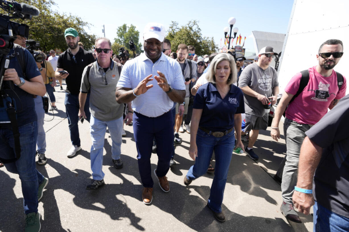 Republican presidential candidate Sen. Tim Scott, R-S.C., walks with Sen. Joni Ernst, R-Iowa, during a visit to the Iowa State Fair, Tuesday, Aug. 15, 2023, in Des Moines, Iowa.