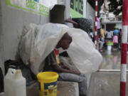 A youth displaced by the gang violence living at a school sits under plastic as rain from Tropical Storm Franklin falls in Port-au-Prince, Haiti, Wednesday, Aug. 23, 2023.