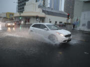 A car turns onto flooded Cooke Street Dec. 6, 2021, in Honolulu.