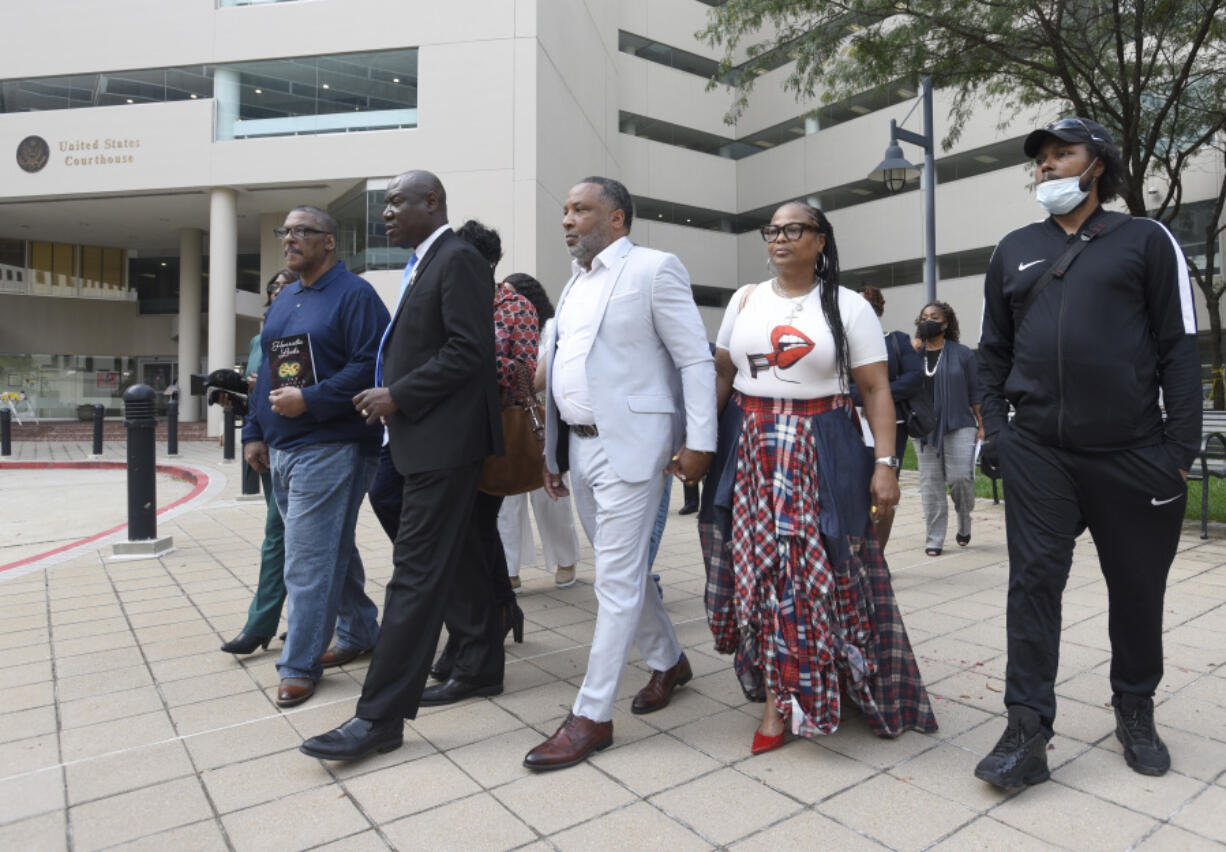 FILE - Attorney Ben Crump, second from left, walks with Ron Lacks, left, Alfred Lacks Carter, third from left, both grandsons of Henrietta Lacks, and other descendants of Lacks, outside the federal courthouse in Baltimore, Oct. 4, 2021. The family of Henrietta Lacks is settling a lawsuit against a biotechnology company it accuses of improperly profiting from her cells. Their federal lawsuit in Baltimore claimed Thermo Fisher Scientific has made billions from tissue taken without the Black woman's consent from her cervical cancer tumor.