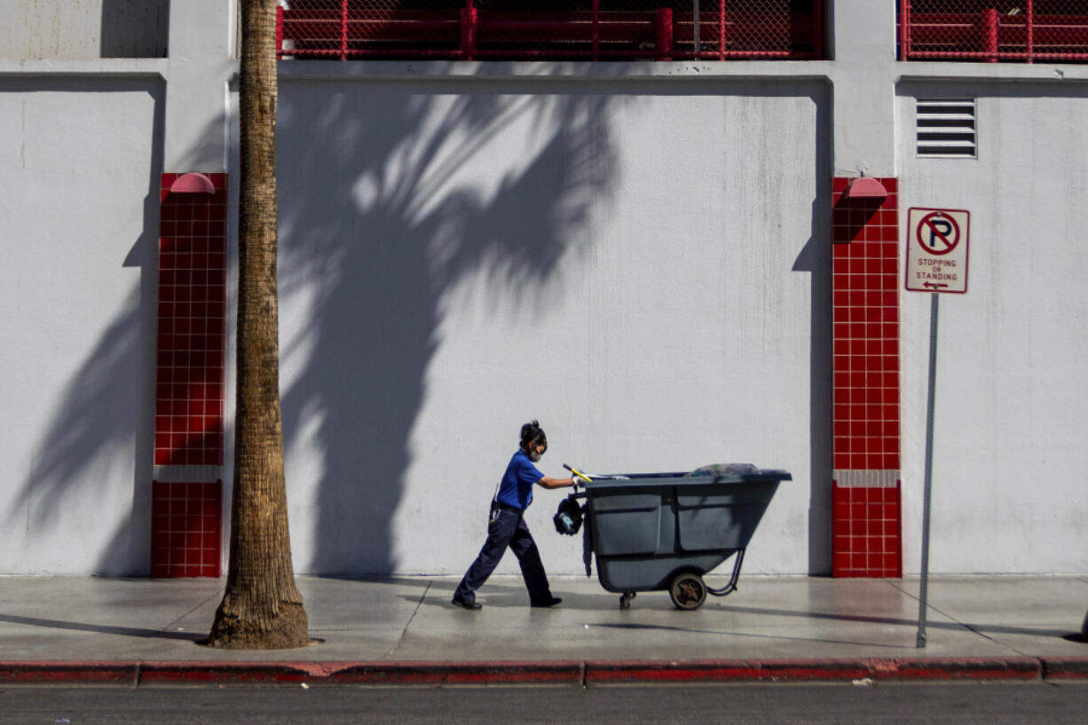 A maintenance worker pushes a refuse cart in the sun, Friday, Aug. 25, 2023, in Las Vegas. A historic heat wave that began blasting the Southwest and other parts of the country this summer is shining a spotlight on one of the harshest, yet least-addressed, effects of climate change in the U.S.: the rising deaths and injuries of people who work in extreme heat, whether inside hot warehouses and kitchens or outside under the blazing sun. Many of them are migrants in low-wage jobs.