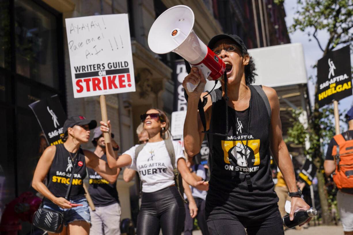 A strike captain, right, leads the chants as strikers walk a picket line outside Warner Bros., Discovery, and Netflix offices in Manhattan, Friday, Aug. 18, 2023. The WGA and SAG-AFTRA held a joint Latine Picket, presented by the WGAE Latine Writers Salon, the WGAW Latinx Writers Committee, and the SAG-AFTRA National Latino Committee.