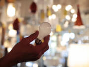 FILE - Manager Nick Reynoza holds a 100-watt incandescent light bulb at Royal Lighting in Los Angeles, Jan. 21, 2011. New federal rules governing the energy efficiency of lighting systems went into full effect Tuesday, effectively ending the sale and manufacture of bulbs that trace their origin to an 1880 Thomas Edison patent. (AP Photo/Jae C.