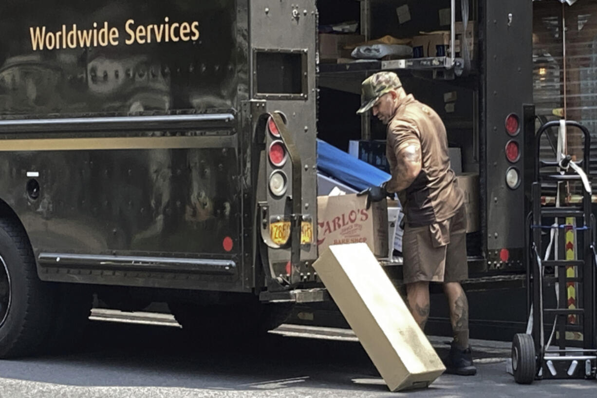 File - A United Parcel Service driver sorts his deliveries, on New York's Upper West Side, Saturday, July 15, 2023. Higher pay is one issue driving strikes among Hollywood writers and actors, and was a focus on the Teamsters union in their negotiations with UPS, which led to large pay gains.