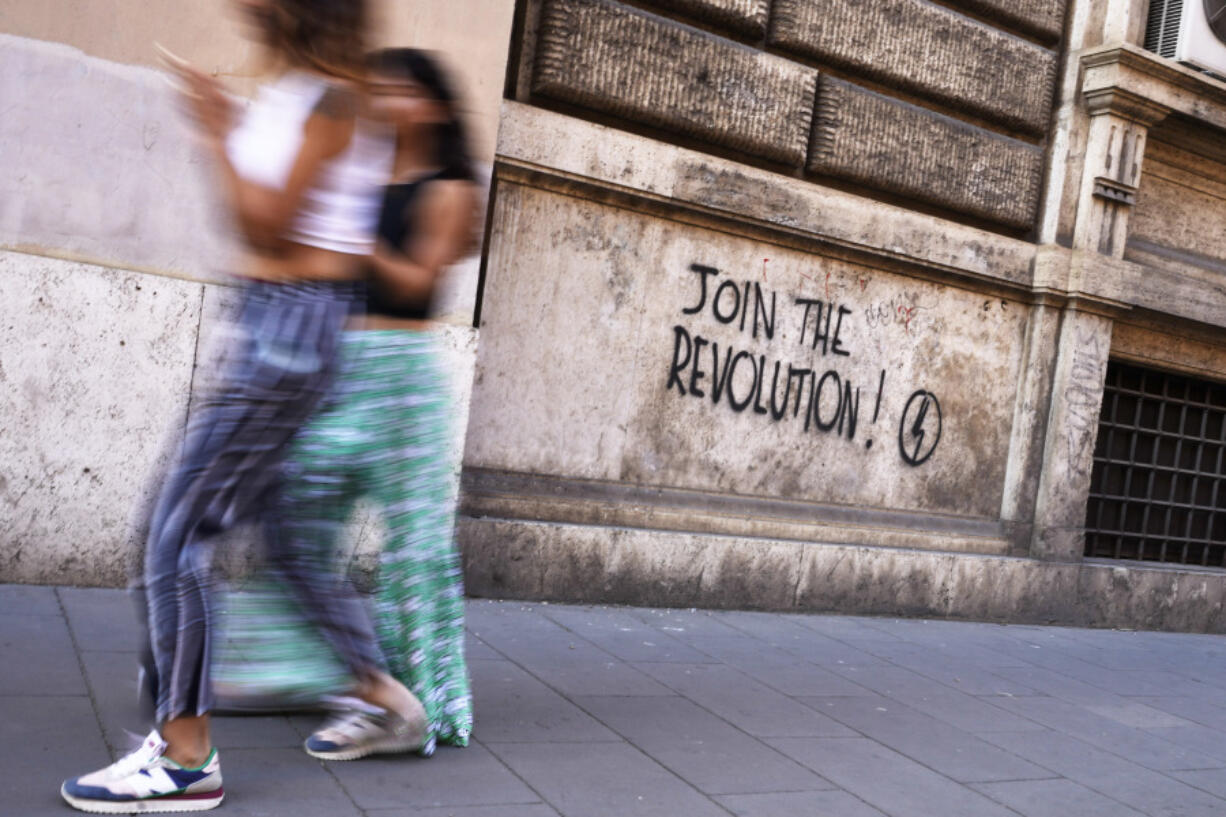 People walk past a mural by right-wing students movement called "Blocco Studentesco" (Student Block) in downtown Rome, Sunday, Aug. 13 ,2023.