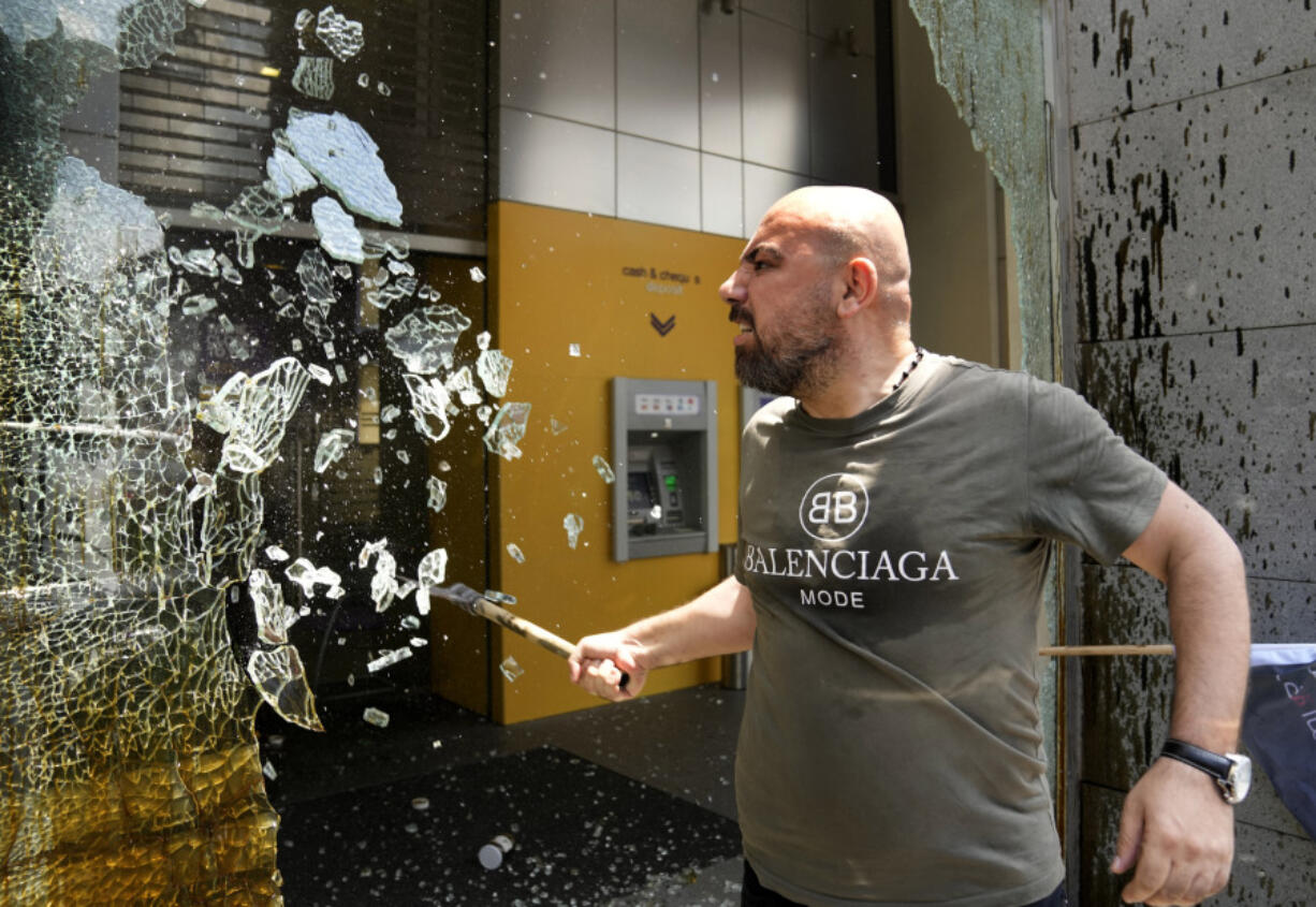 FILE - A man smashes windows at Byblos Bank during a protest demanding the release of depositors' trapped savings, in Beirut, Lebanon, Thursday, June 15, 2023. Four years into Lebanon's historic economic meltdown, Lebanon's elites are pushing an economic recovery plan that would sidestep critical reforms demanded by the International Monetary Fund.