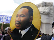 FILE - A man holds a portrait of the Rev. Martin Luther King, Jr., at the Martin Luther King Jr. Memorial during the March on Washington, Friday Aug. 28, 2020, in Washington.