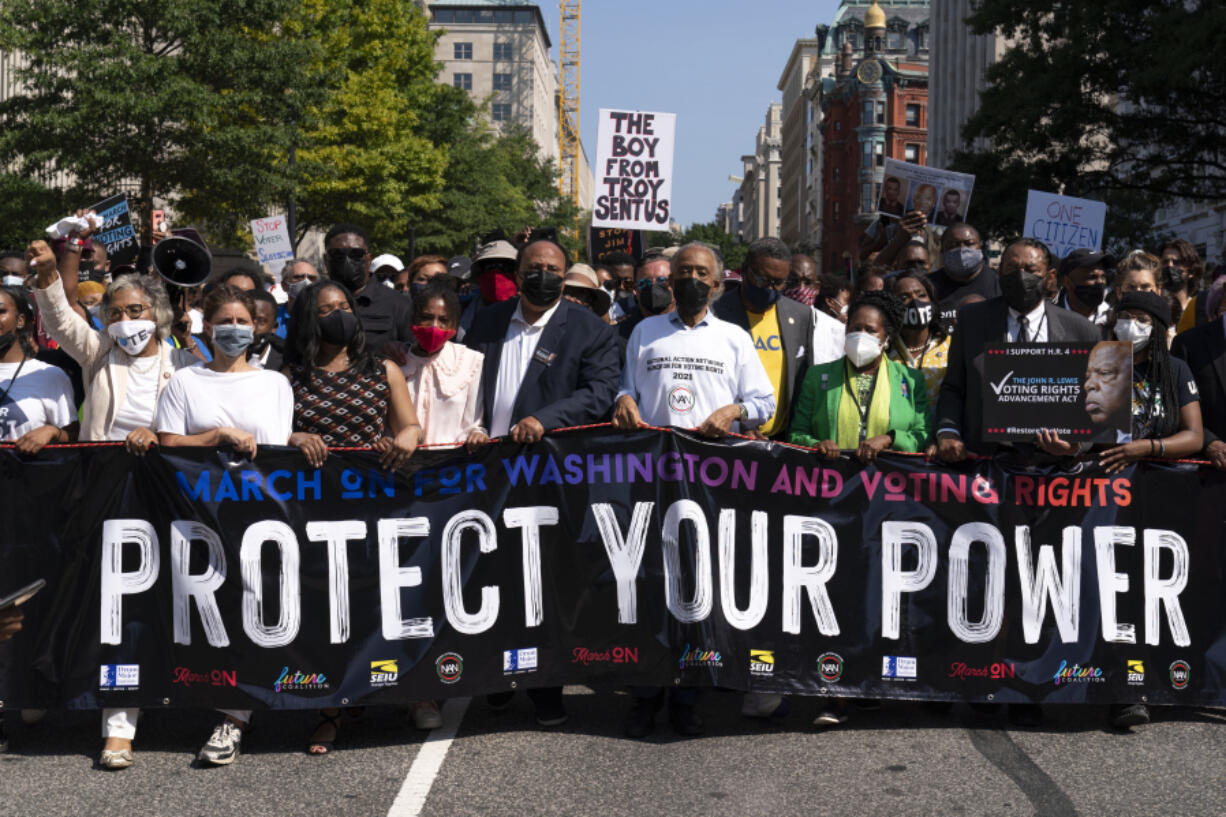 FILE - The Rev. Al Sharpton, foreground third from right, holds a banner with Martin Luther King, III, Rep. Sheila Jackson Lee, D-Texas, second from right, and Rep. Al Green, D-Texas, right, and others, during the march to call for sweeping protections against a further erosion of the Voting Rights Act of 1965, Saturday, Aug. 28, 2021, in Washington.