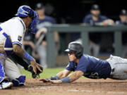 Seattle Mariners' Dylan Moore, left, beats the tag by Kansas City Royals catcher Salvador Perez to score on a sacrifice fly hit by Teoscar Hernandez during the eighth inning of a baseball game Wednesday, Aug. 16, 2023, in Kansas City, Mo.