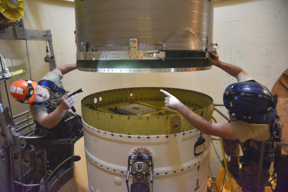 FILE - In this image provided by the U.S. Air Force, Airman 1st Class Jackson Ligon, left, and Senior Airman Jonathan Marinaccio, 341st Missile Maintenance Squadron technicians connect a re-entry system to a spacer on an intercontinental ballistic missile during a Simulated Electronic Launch-Minuteman test Sept. 22, 2020, at a launch facility near Malmstrom Air Force Base in Great Falls, Mont. The Air Force has temporarily closed two nuclear launch facilities after finding unsafe levels of a likely carcinogen in air samples at a Montana missile base where a striking number of men and women who served have reported cancer diagnoses. (Senior Airman Daniel Brosam/U.S.