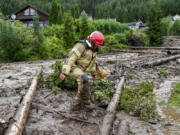 A rescue worker climbs over tree trunks after a mudslide has hit several residential buildings in Bagn in Valdres, Norway, Tuesday, Aug. 8, 2023. Officials in northern Europe are warning people to stay inside as stormy weather batters the region. Storm Hans has cancelled ferries, delayed flights, flooded streets and injured people. Norwegian authorities expected "extremely heavy rainfall" on Tuesday.