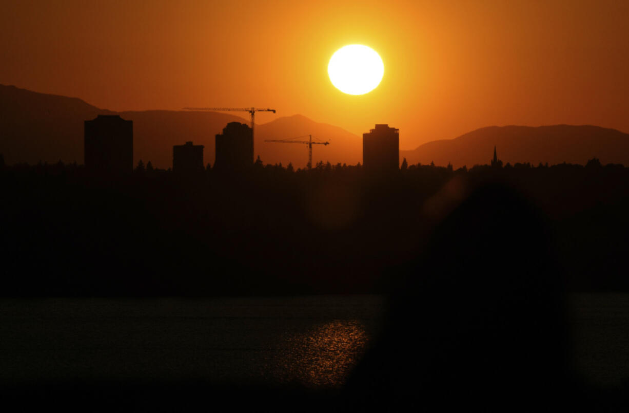 FILE - The sun sets over the University District in Seattle, May 13, 2023, seen from 520 Bridge View Park in Medina, Wash. Two people may have died in a record-shattering heat wave in the Pacific Northwest this week, officials said on Wednesday, Aug. 16.