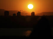 FILE - The sun sets over the University District in Seattle, May 13, 2023, seen from 520 Bridge View Park in Medina, Wash. Two people may have died in a record-shattering heat wave in the Pacific Northwest this week, officials said on Wednesday, Aug. 16.