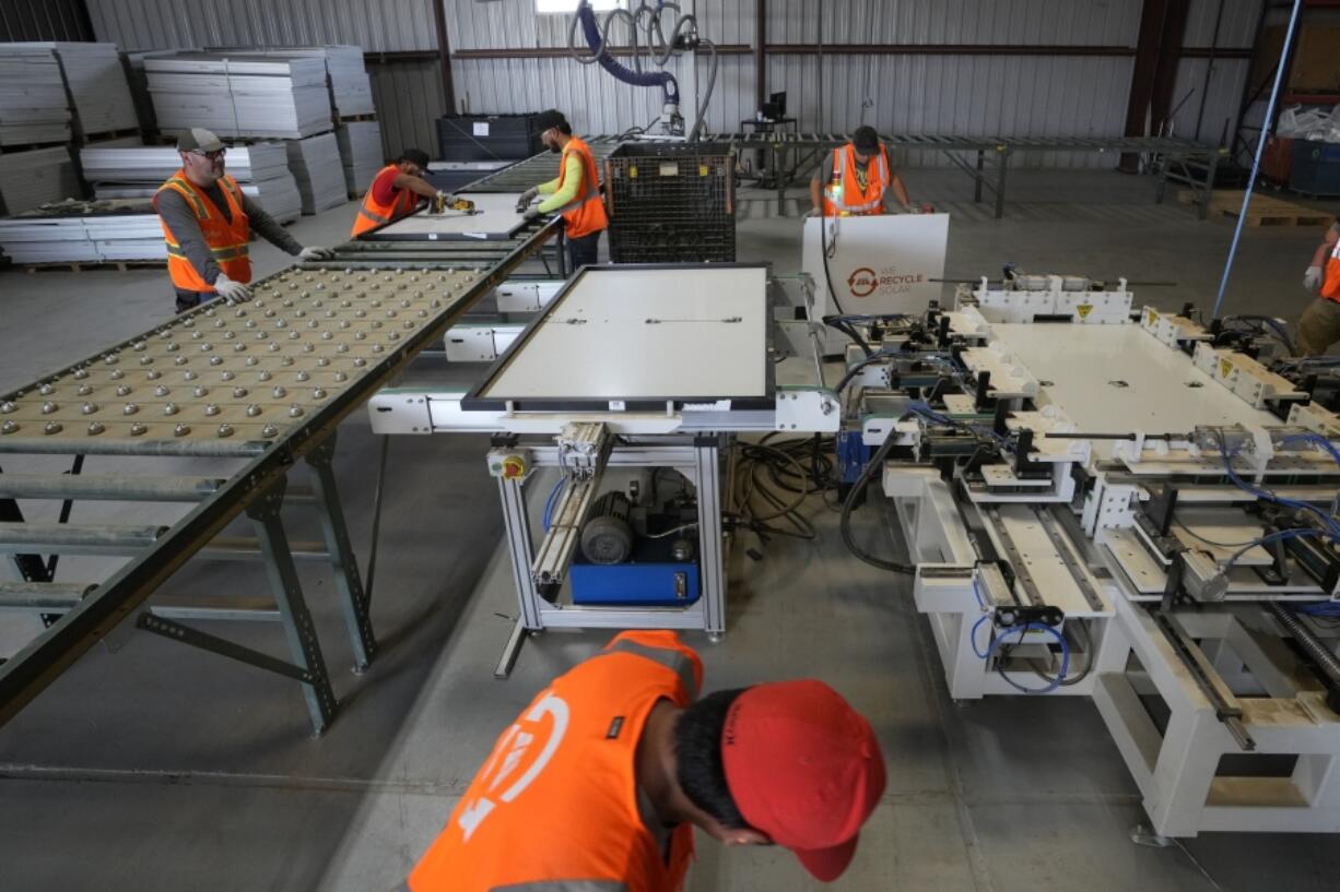 Workers take apart solar panels as they begin the recycling process at We Recycle Solar on Tuesday, June 6, 2023, in Yuma, Ariz. North America's first utility-scale solar panel recycling plant opened to address what founders of the company call a "tsunami" of solar waste, as technology that became popular in the early 2000s rapidly scales up.