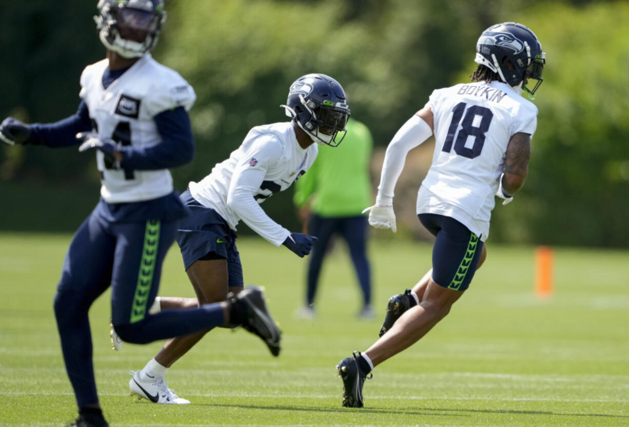 Seattle Seahawks cornerback Devon Witherspoon, center, runs a drill with cornerback Lance Boykin (18) during a "Back Together Weekend" event at the NFL football team's training facility, Sunday, July 30, 2023, in Renton, Wash.