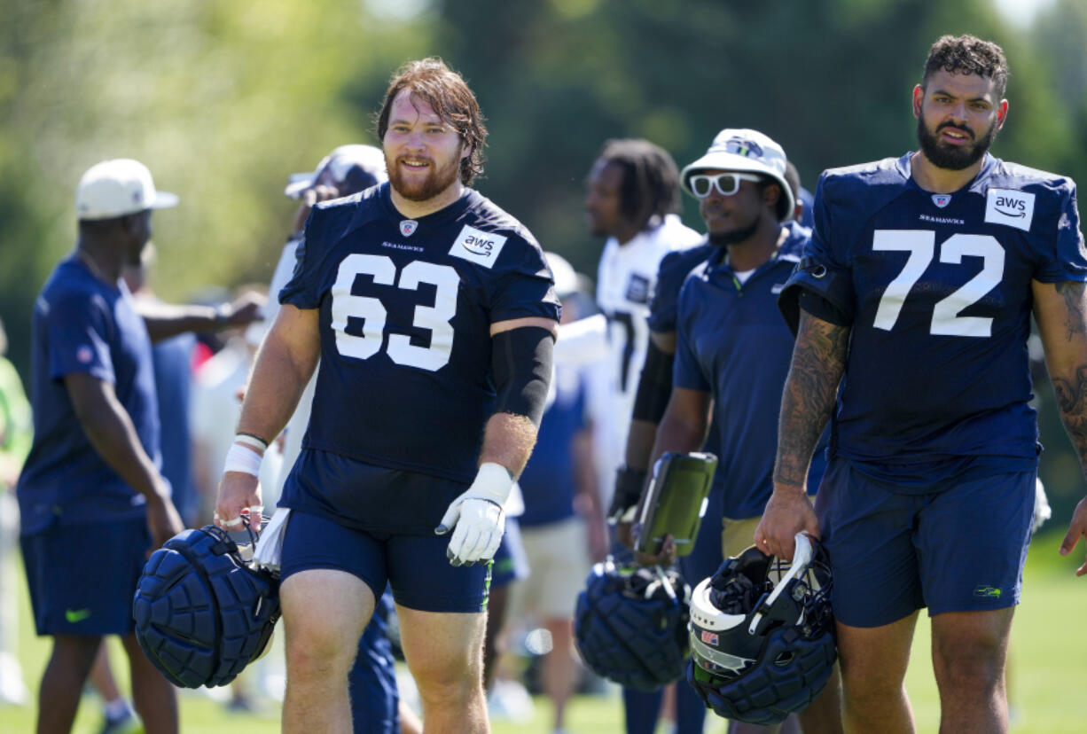 Seattle Seahawks center Evan Brown (63) walks off the field with offensive tackle Abraham Lucas (72) after the NFL football team's training camp, Thursday, Aug. 3, 2023, in Renton, Wash.