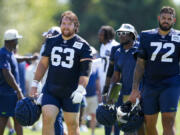Seattle Seahawks center Evan Brown (63) walks off the field with offensive tackle Abraham Lucas (72) after the NFL football team's training camp, Thursday, Aug. 3, 2023, in Renton, Wash.