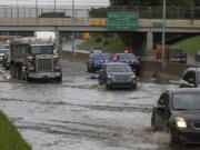 Dozens of vehicles drive through a flooded section of I-94 and Livernois, in Detroit, on Friday, Aug. 25, 2023.