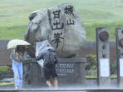 People struggle to hold onto their umbrellas in the rain and wind as the tropical storm named Khanun approaches to the Korean Peninsular, on Jeju Island, South Korea, Wednesday, Aug. 9, 2023. Dozens of flights and ferry services were grounded in South Korea on Wednesday ahead of the tropical storm that has dumped heavy rain on Japan's southwestern islands for more than a week.