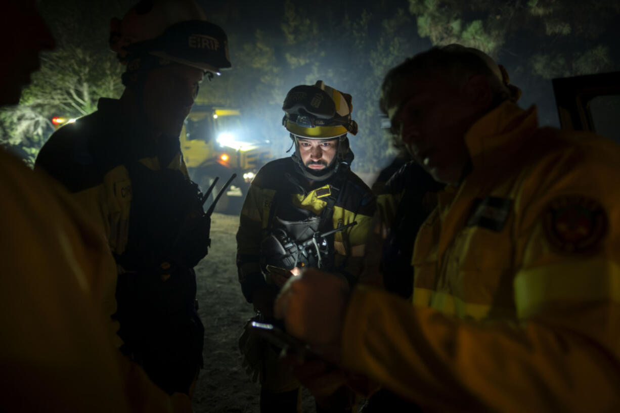 Emergency crews and firefighters work near the fire advancing through the forest toward the town of El Rosario in Tenerife, Canary Islands, Spain on Friday, Aug. 18, 2023. Officials say a wildfire is burning out of control through the Spanish Canary Island of Tenerife, affecting nearly 8,000 people who have been evacuated or ordered to stay indoors.