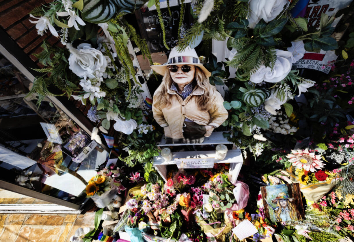 A photo of store owner Laura Ann Carleton surrounded by flowers and Pride flags and placed on memorial outside her store in the Studio City section of Los Angeles, Wednesday, Aug. 23, 2023. Authorities say a 27-year-old man was killed by California sheriff's deputies over the weekend after he fatally shot Carleton, outside her store in Cedar Glen, Calif. roughly 60 miles (96 kilometers) east of downtown Los Angeles. Investigators determined that prior to the shooting the suspect tore down a Pride, or rainbow, flag that was hanging in front of the store and yelled many homophobic slurs toward Carleton.