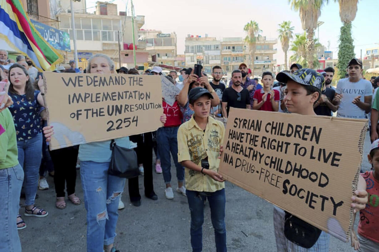 In this photo released by Suwayda24, people hold placards during a protest in the southern city of Sweida, Syria, Saturday, Aug 26, 2023. Angry protesters raided the local offices of the ruling Baath party in a southern Syrian province Wednesday, as protests intensified against the country's government during a severe economic and financial crisis battering the war-torn country.