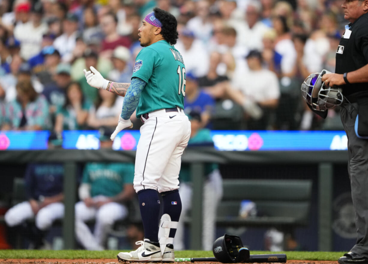 Seattle Mariners' Kolten Wong removes his batting gear after striking out swinging against the Detroit Tigers to end the third inning of a baseball game Saturday, July 15, 2023, in Seattle.