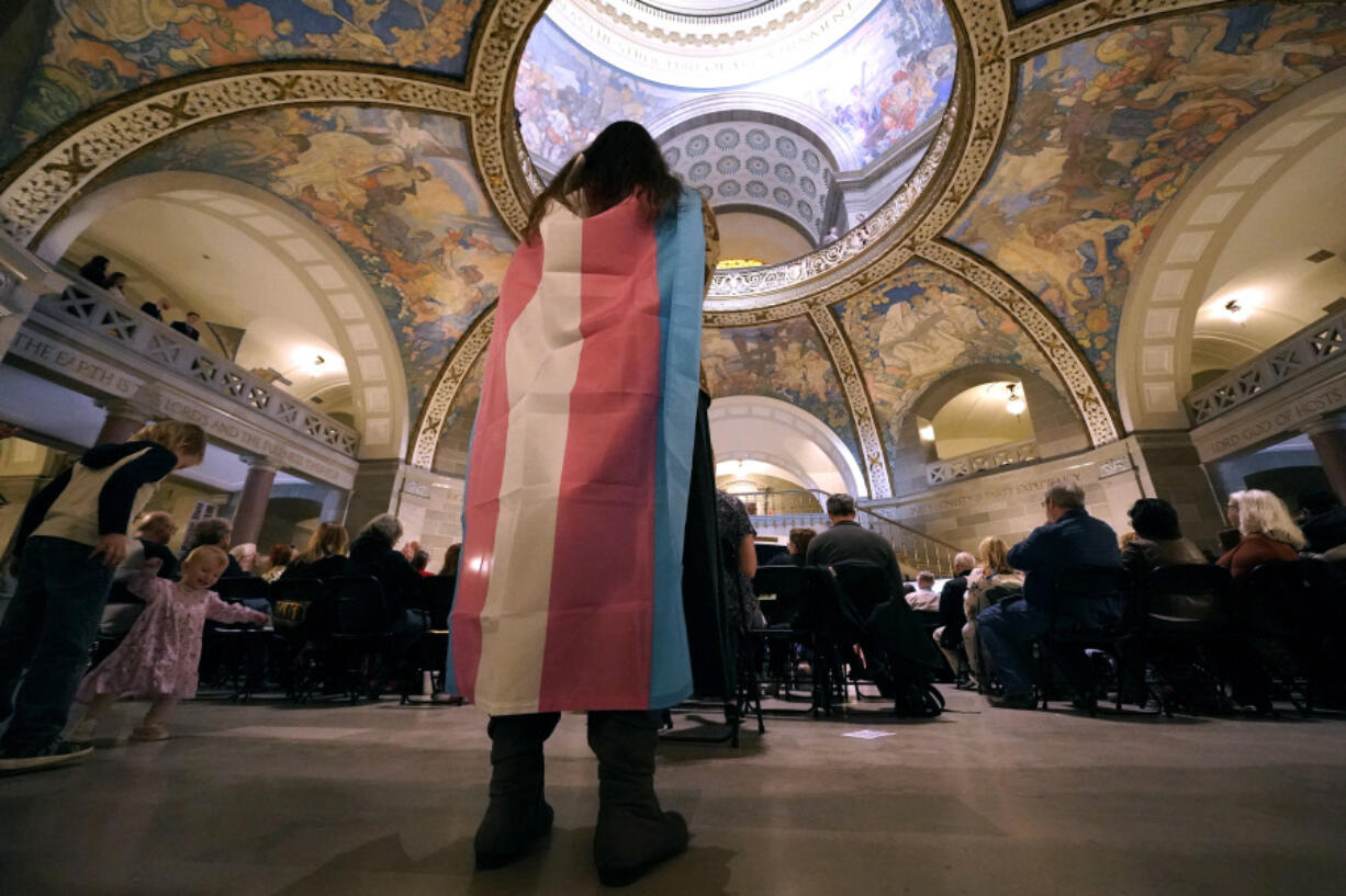 FILE - Glenda Starke wears a transgender flag as a counter protest during a rally in favor of a ban on gender-affirming health care legislation, March 20, 2023, at the Missouri Statehouse in Jefferson City, Mo. The American Academy of Pediatrics on Thursday, Aug. 3, 2023, reaffirmed its support for gender-affirming medical care for transgender children as the treatments face a growing push for bans and restrictions from Republican lawmakers.