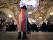 FILE - Glenda Starke wears a transgender flag as a counter protest during a rally in favor of a ban on gender-affirming health care legislation, March 20, 2023, at the Missouri Statehouse in Jefferson City, Mo. The American Academy of Pediatrics on Thursday, Aug. 3, 2023, reaffirmed its support for gender-affirming medical care for transgender children as the treatments face a growing push for bans and restrictions from Republican lawmakers.