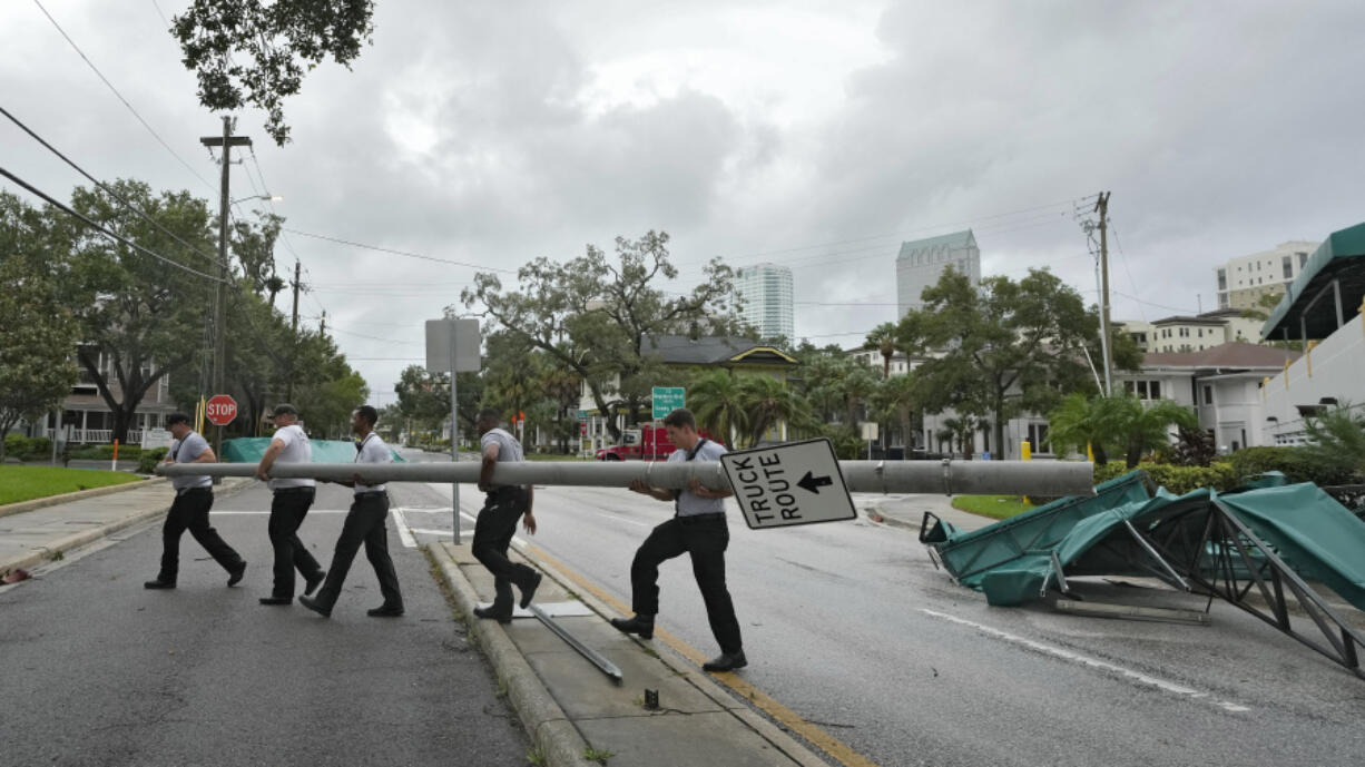 Members of the Tampa Fire Rescue Dept., remove a street pole after large awnings from an apartment building blew off from winds associated with Hurricane Idalia Wednesday, Aug. 30, 2023, in Tampa, Fla. Idalia made landfall earlier this morning along the Big Bend of the state.