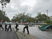 Members of the Tampa Fire Rescue Dept., remove a street pole after large awnings from an apartment building blew off from winds associated with Hurricane Idalia Wednesday, Aug. 30, 2023, in Tampa, Fla. Idalia made landfall earlier this morning along the Big Bend of the state.