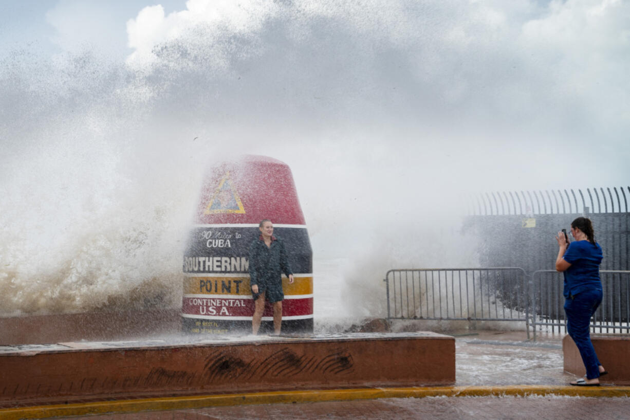 Visitors to the Southernmost Point buoy brave the waves for a few cell phone photos as Hurricane Idalia passes the Florida Keys some 175 miles to the west, on Tuesday, Aug. 29, 2023 in Key West, Fla.  Much of Florida was in disaster mode on Tuesday with only hours to go before an onslaught from Idalia, forecast to strengthen rapidly into "an extremely dangerous major hurricane" before hitting the Gulf Coast on Wednesday.