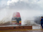 Visitors to the Southernmost Point buoy brave the waves for a few cell phone photos as Hurricane Idalia passes the Florida Keys some 175 miles to the west, on Tuesday, Aug. 29, 2023 in Key West, Fla.  Much of Florida was in disaster mode on Tuesday with only hours to go before an onslaught from Idalia, forecast to strengthen rapidly into "an extremely dangerous major hurricane" before hitting the Gulf Coast on Wednesday.