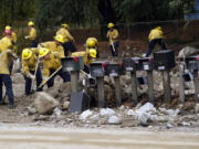 Members of Cal Fire Pilot Rock 6 crew out of Crestline, Calif., clear mud off the side of the road in the aftermath of Tropical Storm Hilary Monday, Aug. 21, 2023, in Yucaipa, Calif.