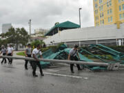 Members of the Tampa Fire Rescue Dept., remove a street pole after large awnings from an apartment building blew off from winds associated with Hurricane Idalia Wednesday, Aug. 30, 2023, in Tampa, Fla. Idalia made landfall earlier this morning along the Big Bend of the state.