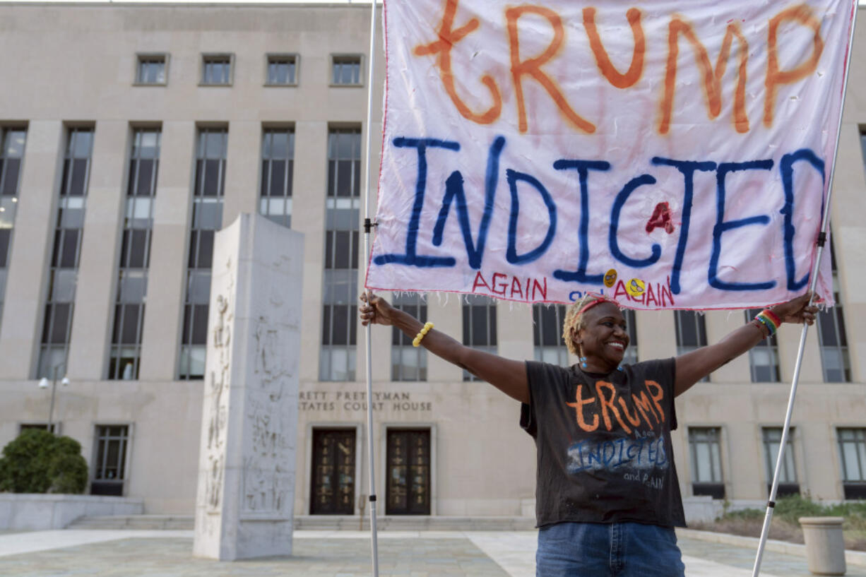 Nadine Seiler protest as she holds a banner outside federal court Tuesday, Aug. 1, 2023 in Washington. Former President Donald Trump has been charged by the Justice Department for his efforts to overturn the results of the 2020 presidential election. The charges include conspiracy to defraud the United States government and witness tampering.