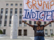 Nadine Seiler protest as she holds a banner outside federal court Tuesday, Aug. 1, 2023 in Washington. Former President Donald Trump has been charged by the Justice Department for his efforts to overturn the results of the 2020 presidential election. The charges include conspiracy to defraud the United States government and witness tampering.