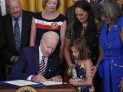 Danielle and Brielle Robinson -- the wife and daughter of Sgt. 1st Class Heath Robinson, who died of cancer two years ago -- watch as President Joe Biden signs the PACT Act on Aug. 10, 2022, in Washington.