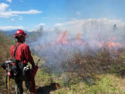 An incarcerated fire crew member assists with a controlled burn in this undated photo.