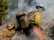 Blue Ridge Hot Shots cut trees and dig a fireline on a steep-sloped mountain to suppress the Dixie Fire in Lassen National Forest, California, in September 2021.