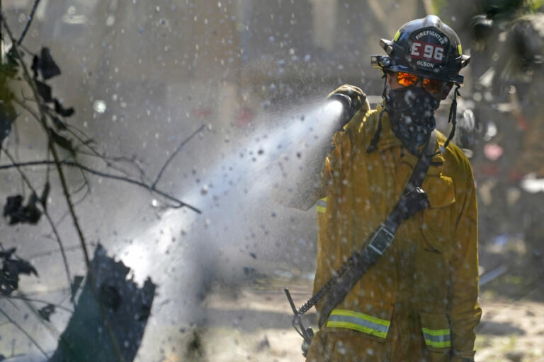 A firefighter works to put out hotspots, Tuesday, Sept. 8, 2020, after a wildfire destroyed homes and outbuildings in Graham, Wash., overnight south of Seattle. (AP Photo/Ted S.