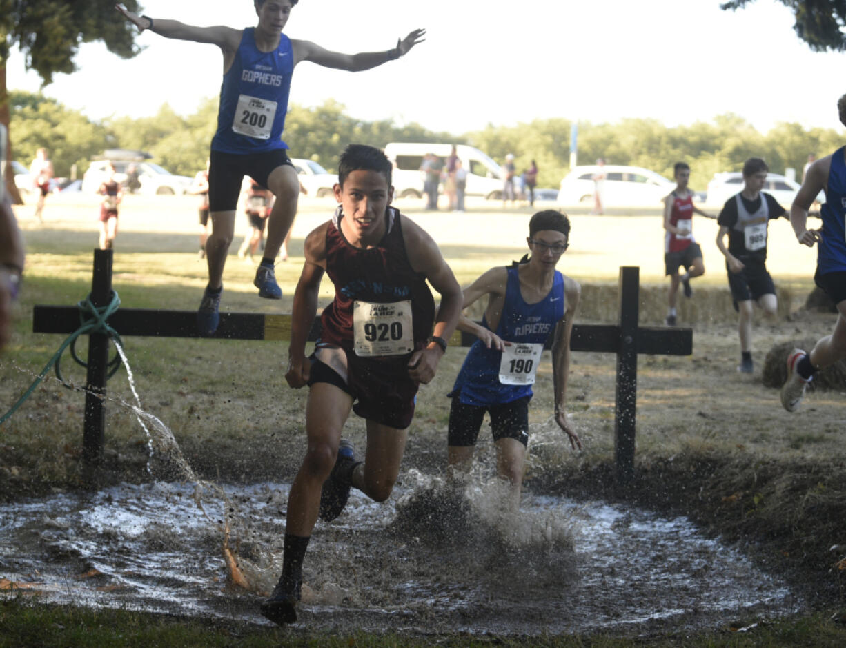 Oscar Hietpas of Stevenson, center, runs through the water pit at the 62nd annual Steve Maas Run-a-Ree on Friday at Hudson's Bay High School. The race is the traditional kickoff event for high school cross country in Southwest Washington.