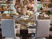 An elegant table is set with beautiful neutral tones, flanked by sleek gray dining chairs.