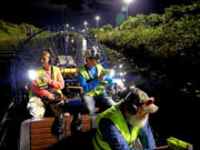 From left: Volunteer Donna Kalil, airboat pilot Dave Hackathorn and volunteer Dave Wagner hunt for pythons in the Everglades west of Weston, Fla., on Aug. 12, 2022.