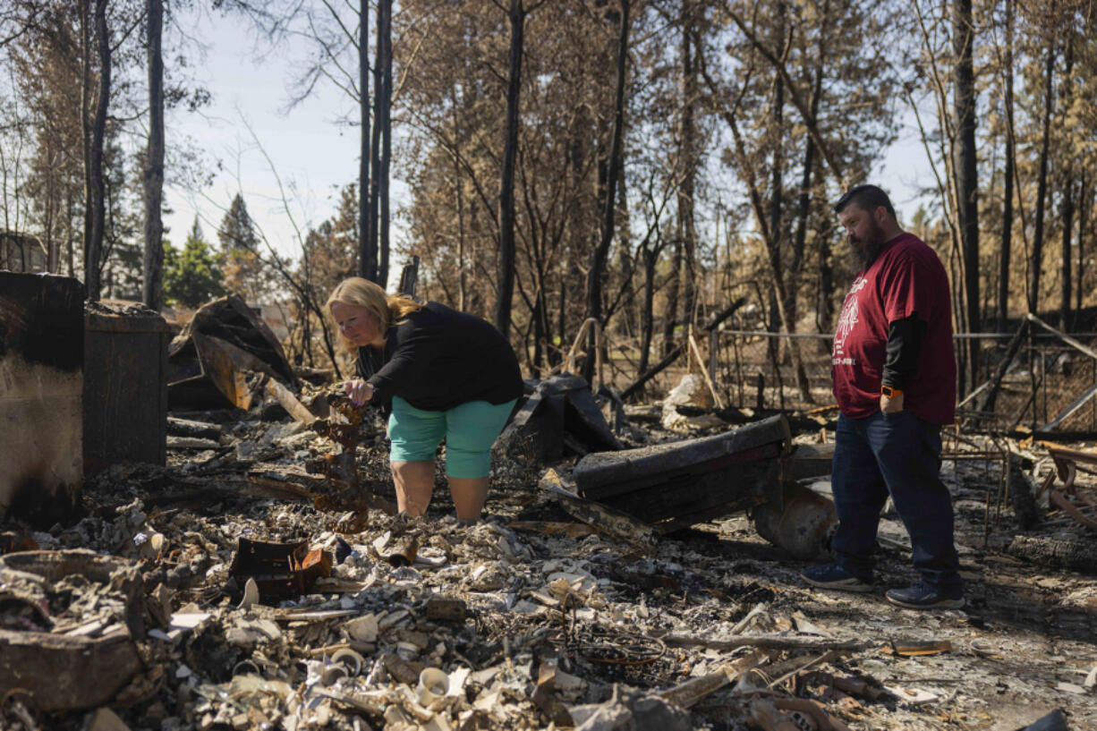 Jennie Tinsley and partner Jacob Bouvette look through the rubble of their home that burned down in the Gray Fire on Aug. 31, 2023.