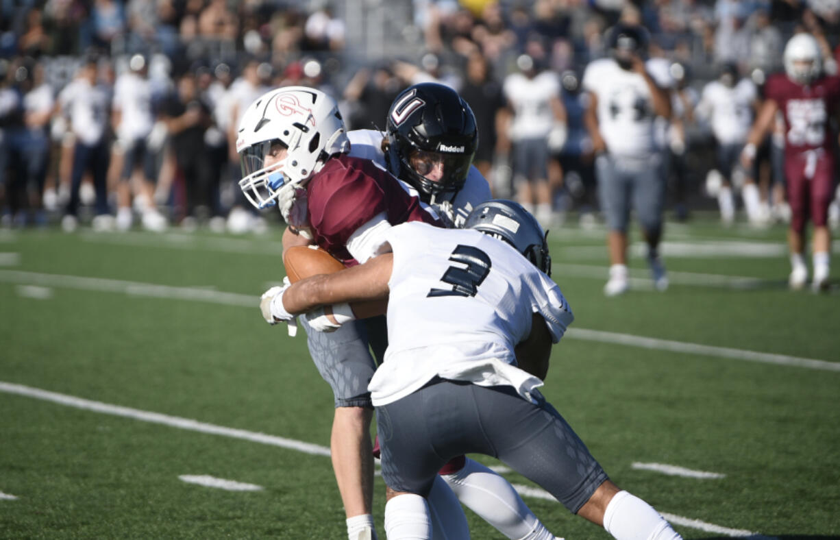 Union's Chase Lofton, center, and Yeshi Tsewang (3) combine to tackle Prairie receiver Jackson Kimball during Union's 27-13 win on Friday, Sept. 23, 2023 at District Stadium in Battle Ground.